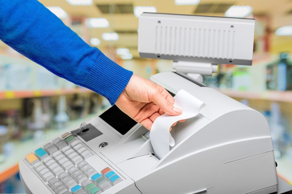 person pulling a receipt out of a register 