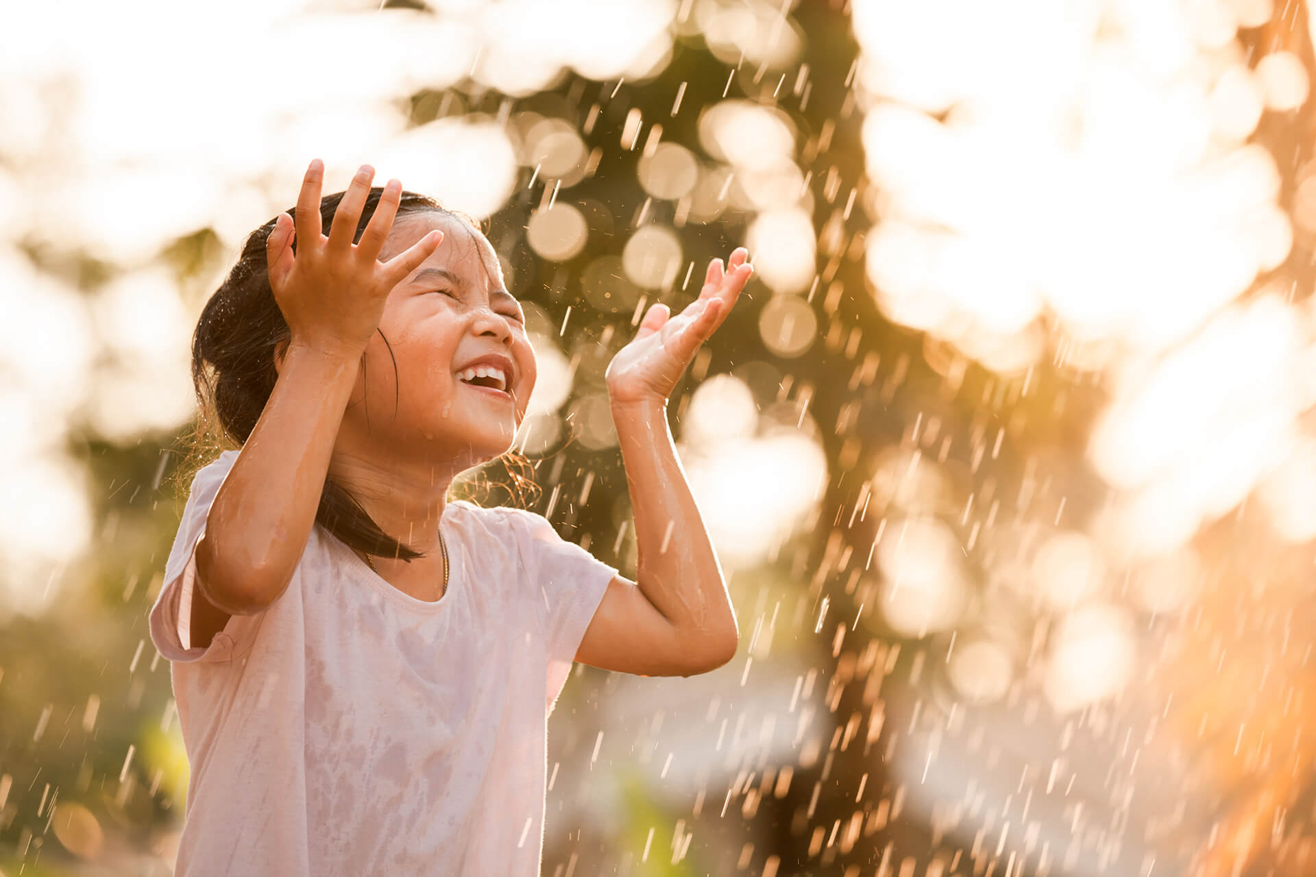 A child plays in a sprinkler