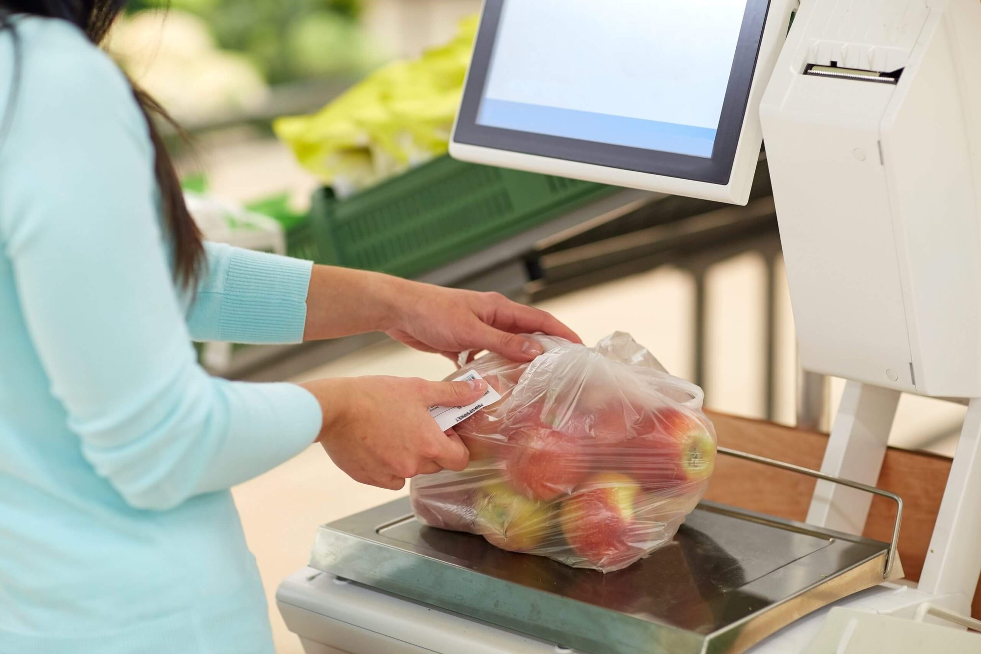 Person scans a bag of apples at a grocery checkout kiosk